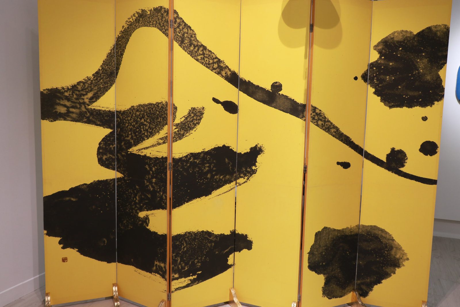 A six-panel gold-leaf screen brushed with sweeping black ink strokes