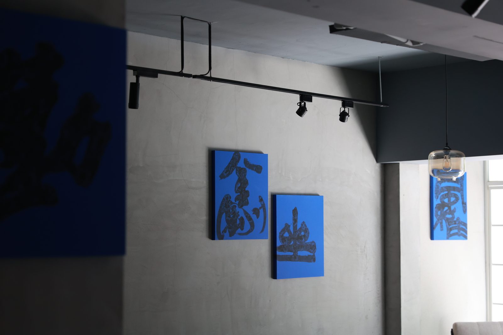 The blue-ground calligraphies hung in a grey gallery room