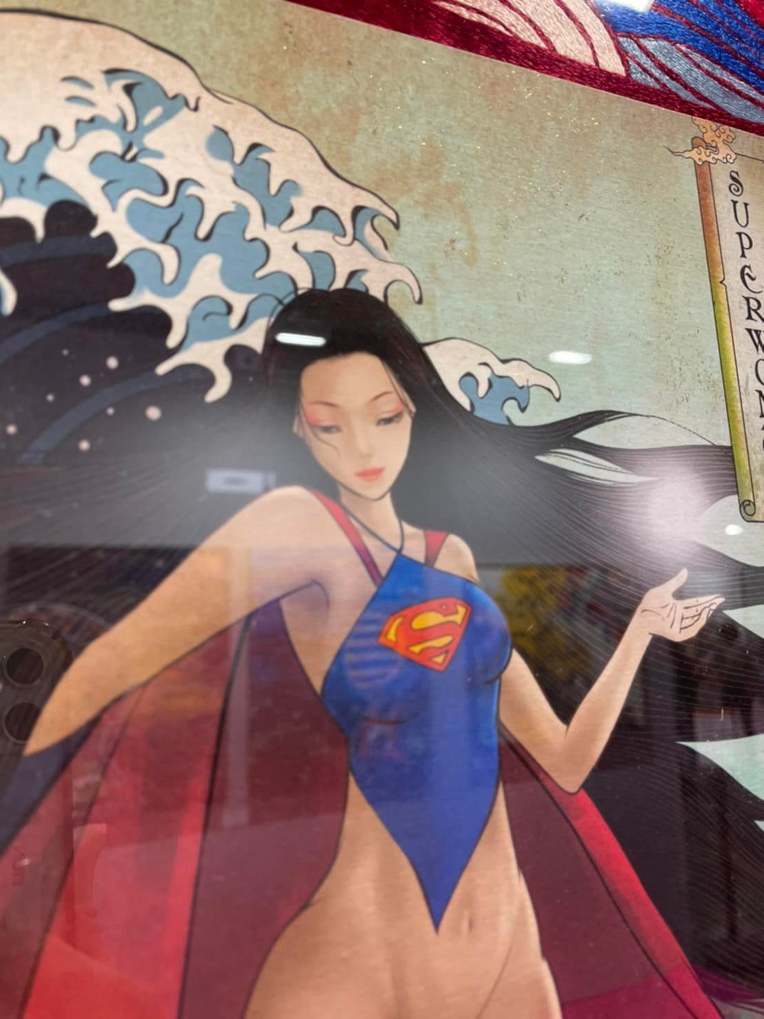 Detail of a Heroine work: a caped heroine in a blue costume against an embroidered wave