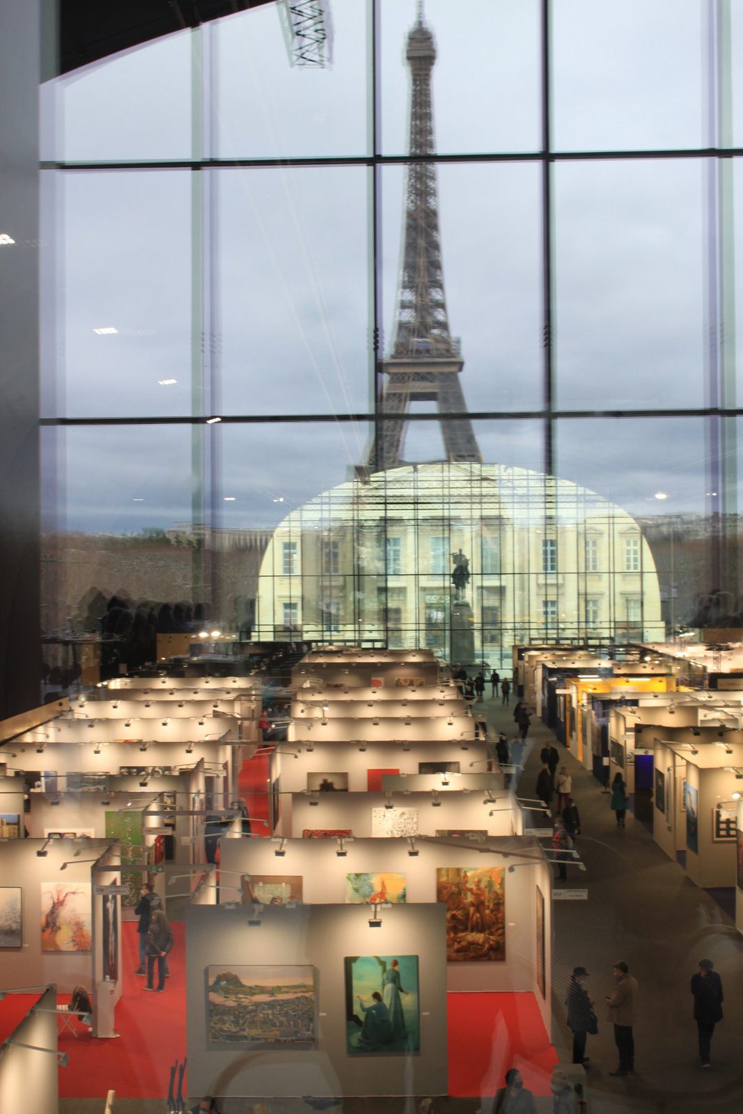 The fair floor of Art Capital under the glass roof of the Grand Palais Éphémère, the Eiffel Tower beyond