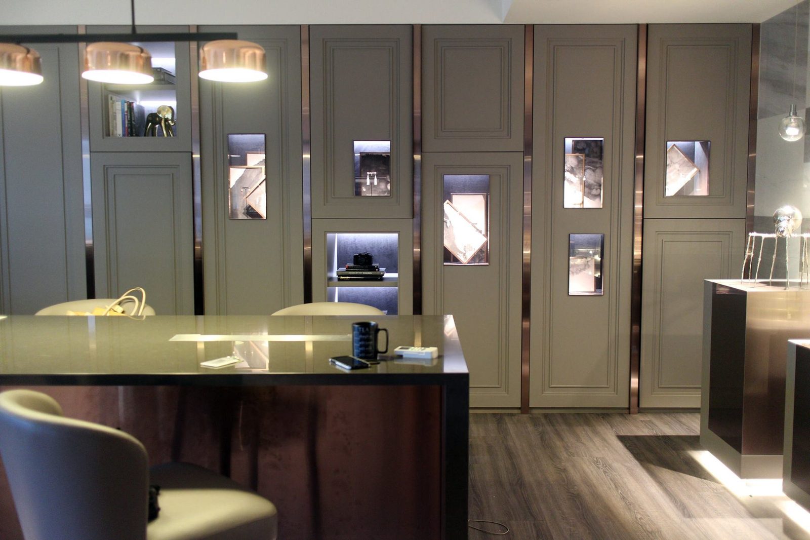 Ink-wash panels in bronze frames behind jewellery in the lit display niches of a Taipei jeweller