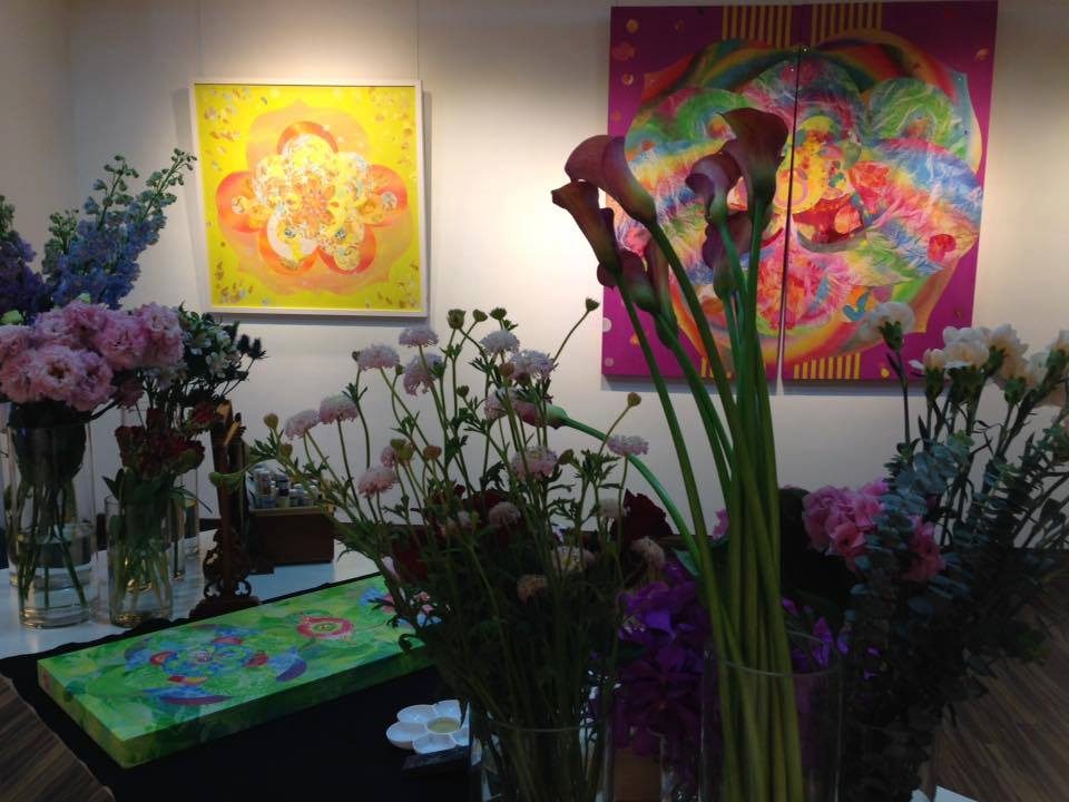 Mineral paintings hung above a flower installation at an exhibition opening