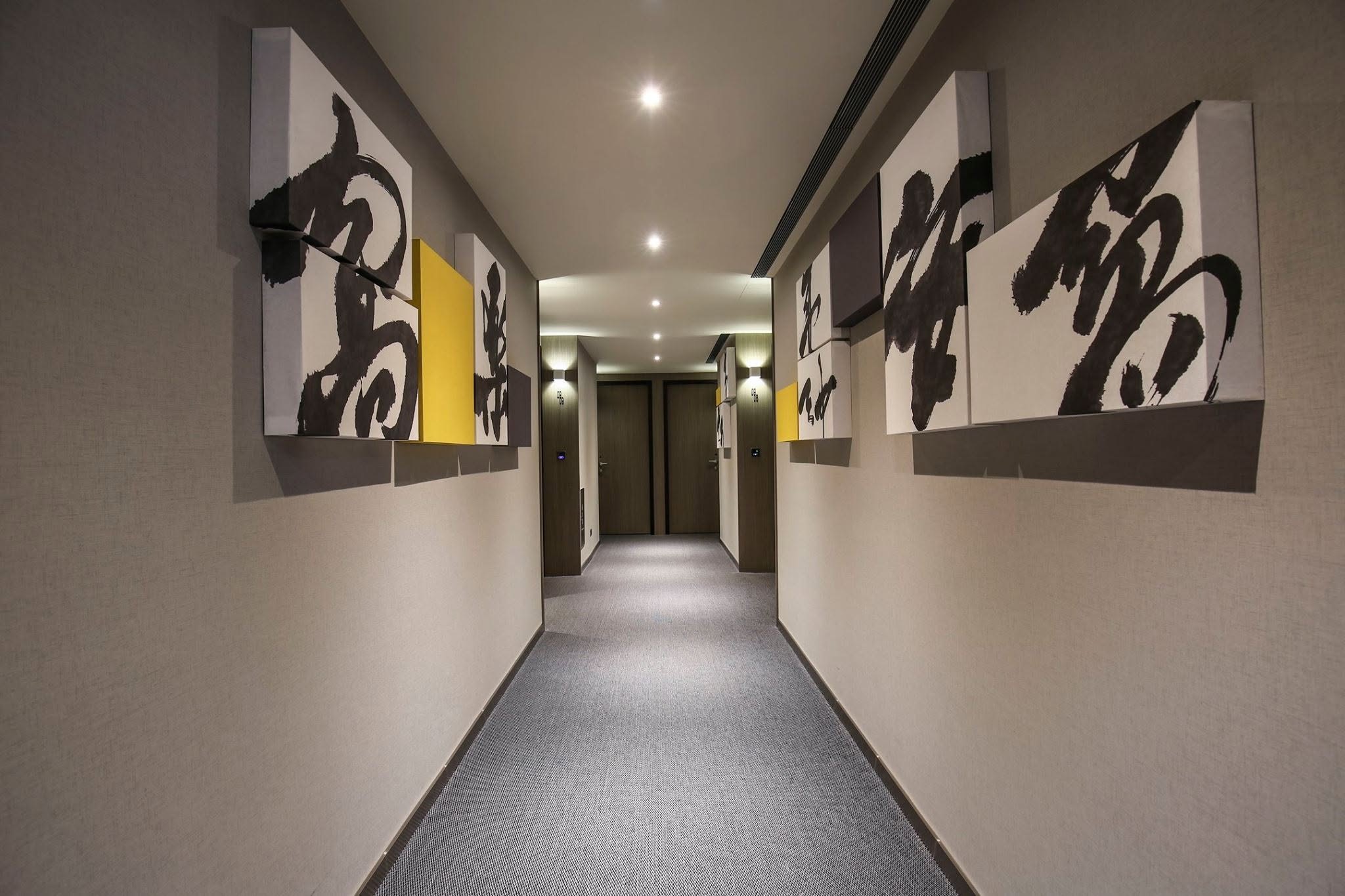 A guest-floor corridor at CityInn Hotel, Taipei: large white canvases of black ink calligraphy, with yellow blocks, line both walls to the far end