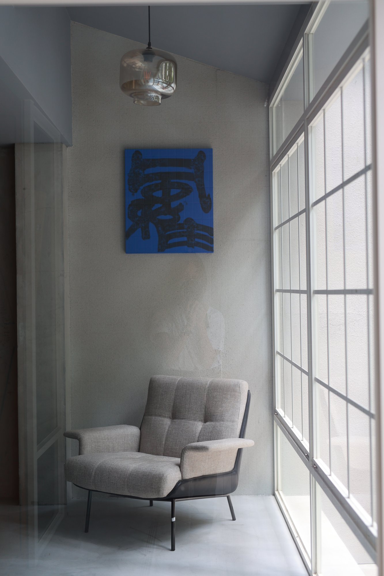 Two of the blue-ground calligraphies in a concrete gallery, lit from the window
