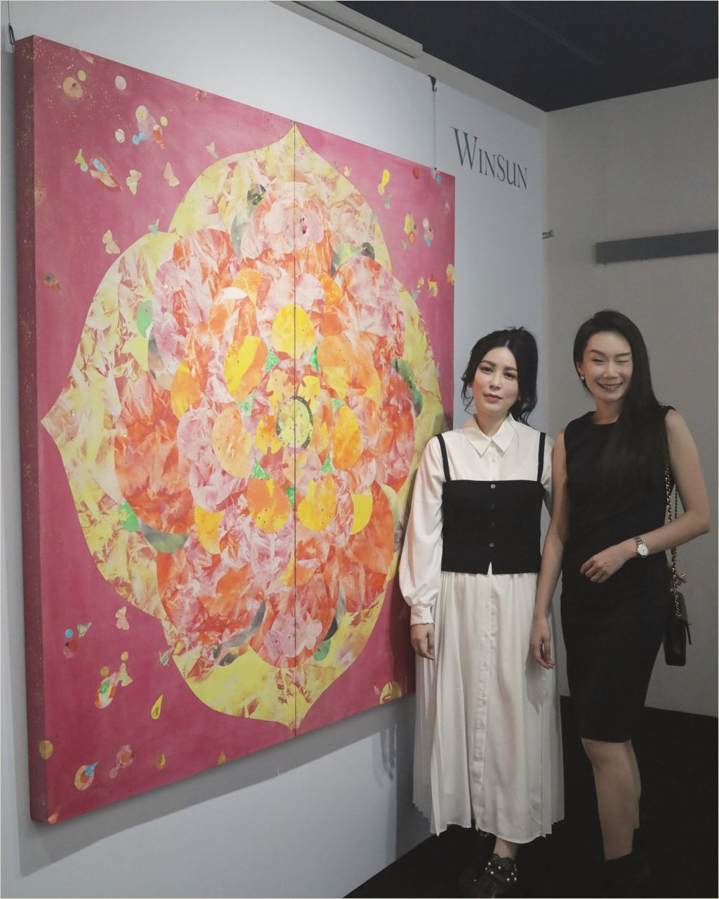 Ku Chi-Chun and a guest beside the Flower of Life diptych, a lotus mandala in yellow and coral across two panels on a crimson ground