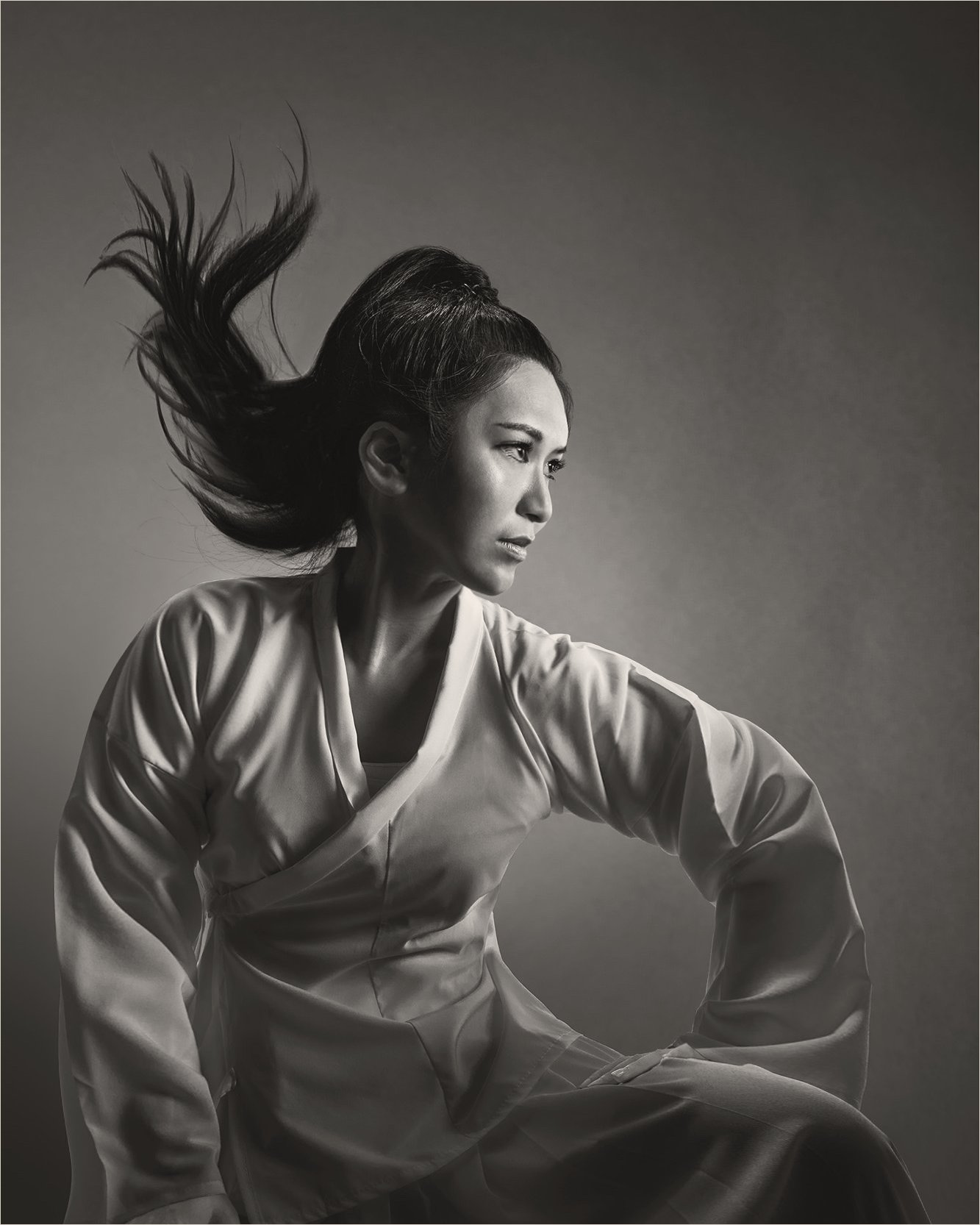 Ku Chi-Chun in a black-and-white robe, hair in motion