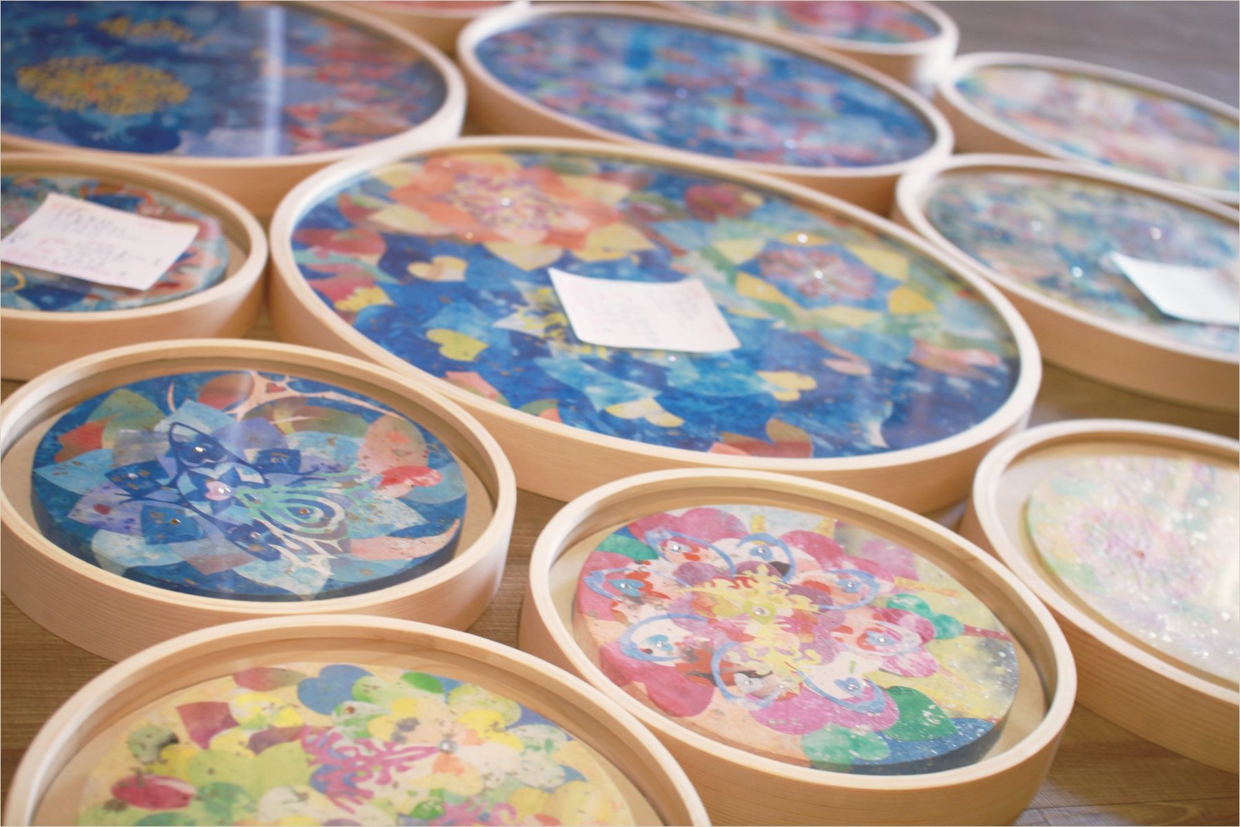 Finished round mineral paintings in wooden frames, stacked on the studio bench