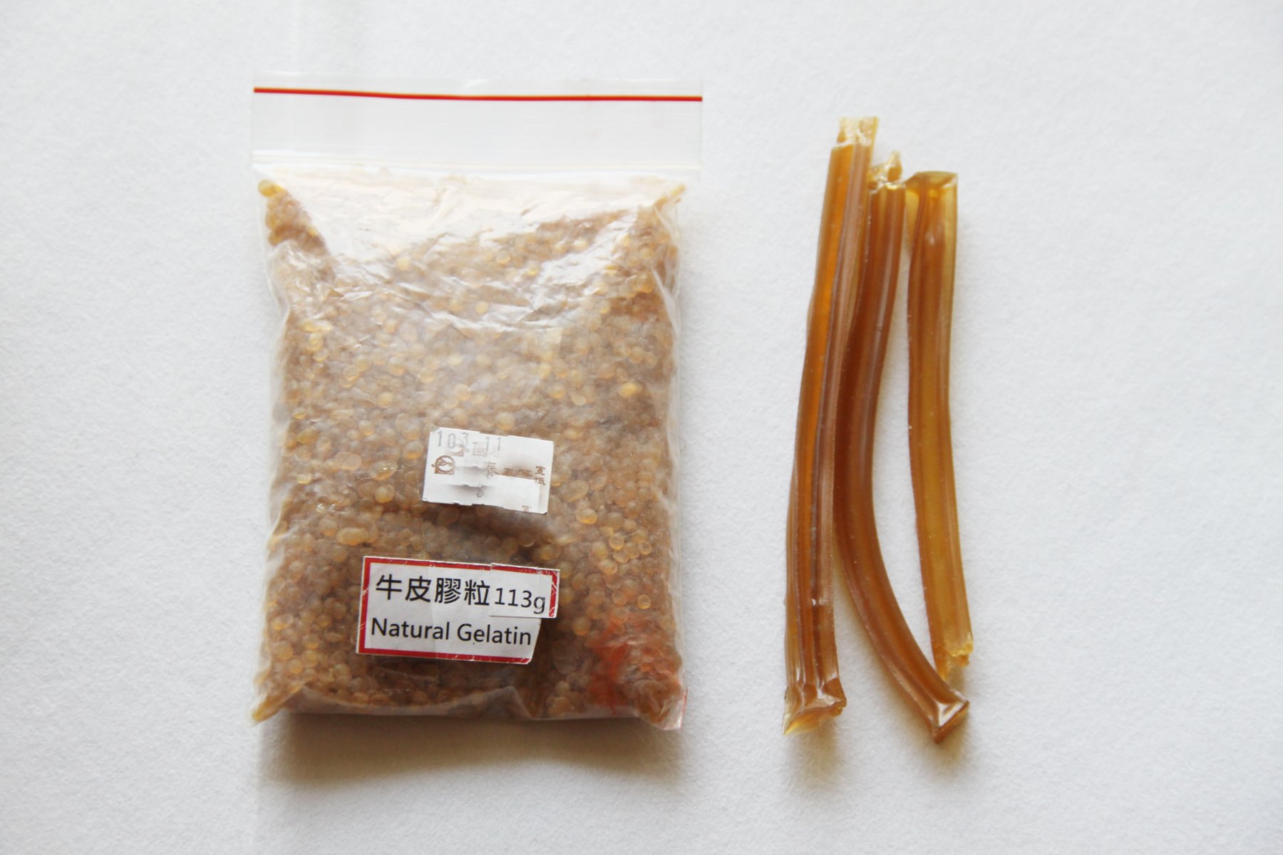 A bag of natural gelatin and sticks of animal glue on white paper