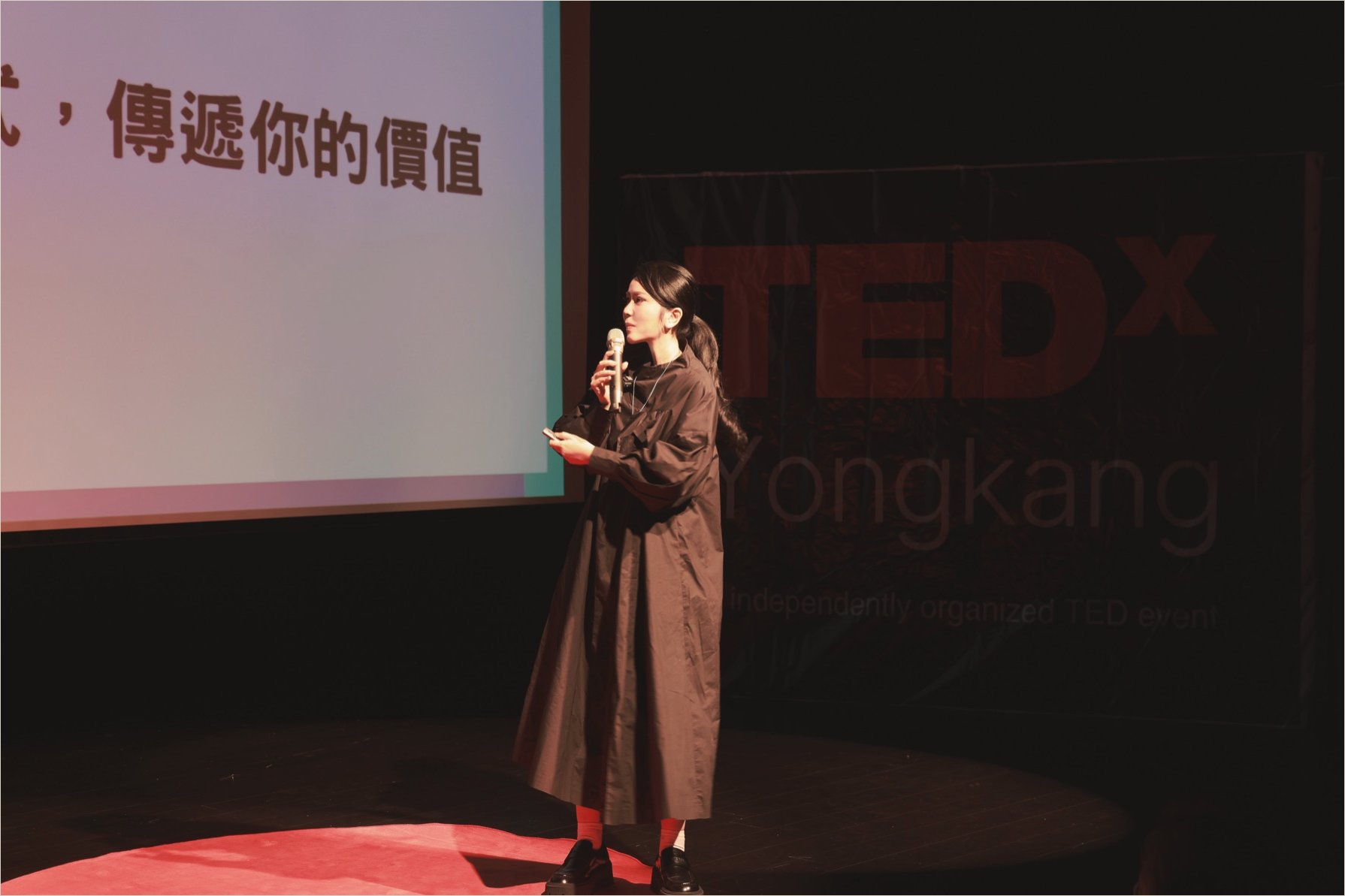 Ku Chi-Chun in profile with a microphone on the TEDxYongkang stage, the TEDx wordmark large at right