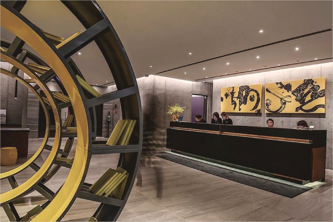 Hotel lobby in Taipei: two large gold-ground calligraphy panels behind the reception desk and a circular yellow bookshelf